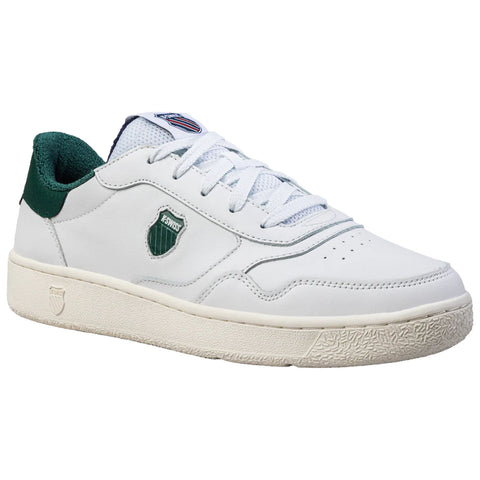 A white athletic shoe with green accents is displayed angled to show its clean lines and texture. The shoe features a logo on the side and a textured rubber sole.