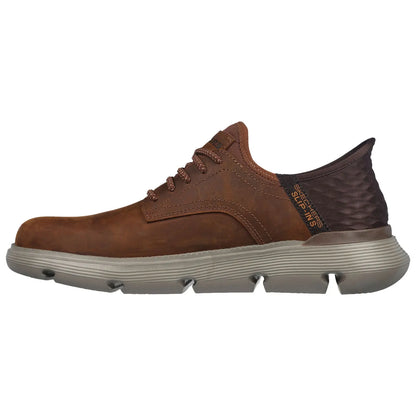 A brown leather shoe with a rounded toe features textured fabric at the heel and laces, set against a white background, emphasizing its casual and stylish design.