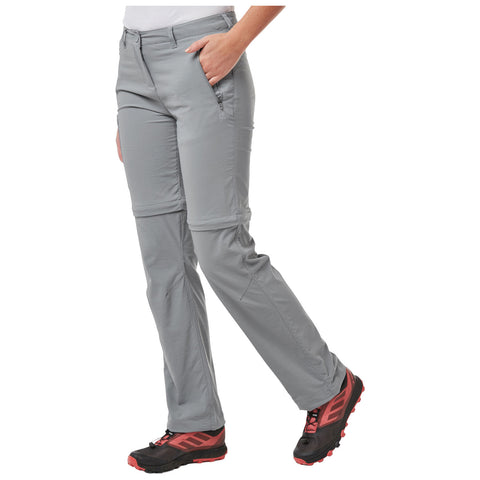 Gray hiking pants, worn by a person standing with one leg forward, feature a zipper pocket on the side, complemented by black and red hiking shoes, set against a white background.