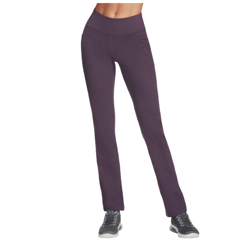 A pair of dark purple leggings stands upright, featuring a high waist and side pockets, paired with gray athletic shoes, suggesting an active lifestyle or workout environment.