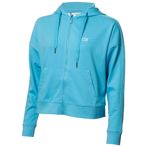 A light blue zip-up hoodie features a front pocket and drawstrings on the hood showcasing the Calvin Klein logo in white on the chest in a neutral background.