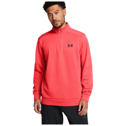 A man stands wearing a bright red quarter-zip pullover with a black logo on the left chest while smiling against a plain white background. He appears relaxed and casual.