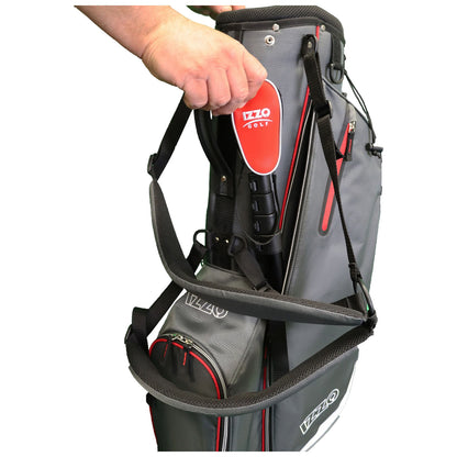 A hand reaches to grasp a golf club stored in a gray and red golf bag with multiple pockets indicating preparation for a game in a golf course environment.