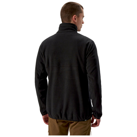 A man stands facing away wearing a black fleece jacket. His head is turned slightly to the right, showcasing the high collar and relaxed fit of the garment. The background is plain white.