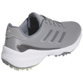 A gray athletic shoe with a textured upper and three stripes on the side is positioned at an angle showing the sole featuring traction elements suitable for sports activities.