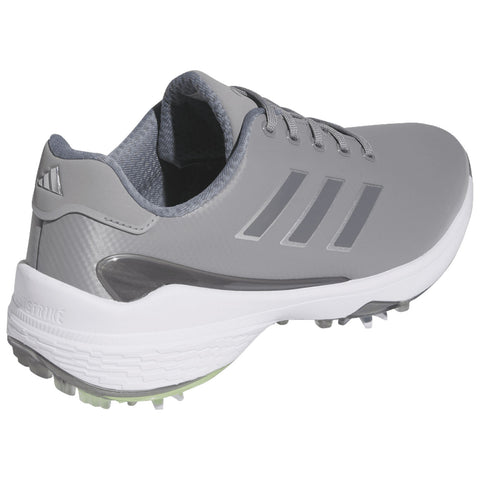 A gray athletic shoe with a textured upper and three stripes on the side is positioned at an angle showing the sole featuring traction elements suitable for sports activities.