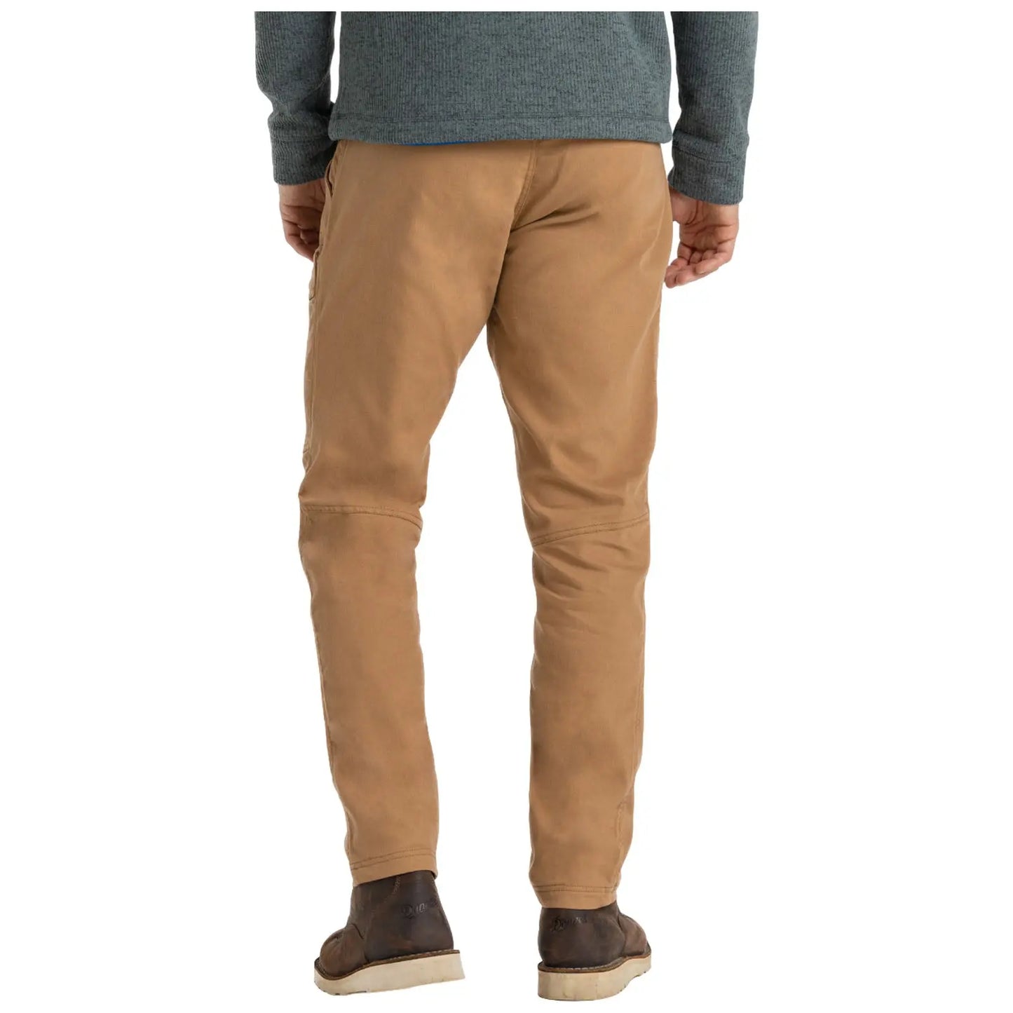 A person is standing with their back facing the viewer wearing light brown pants and a dark sweater in a casual setting. The footwear is dark and casual.