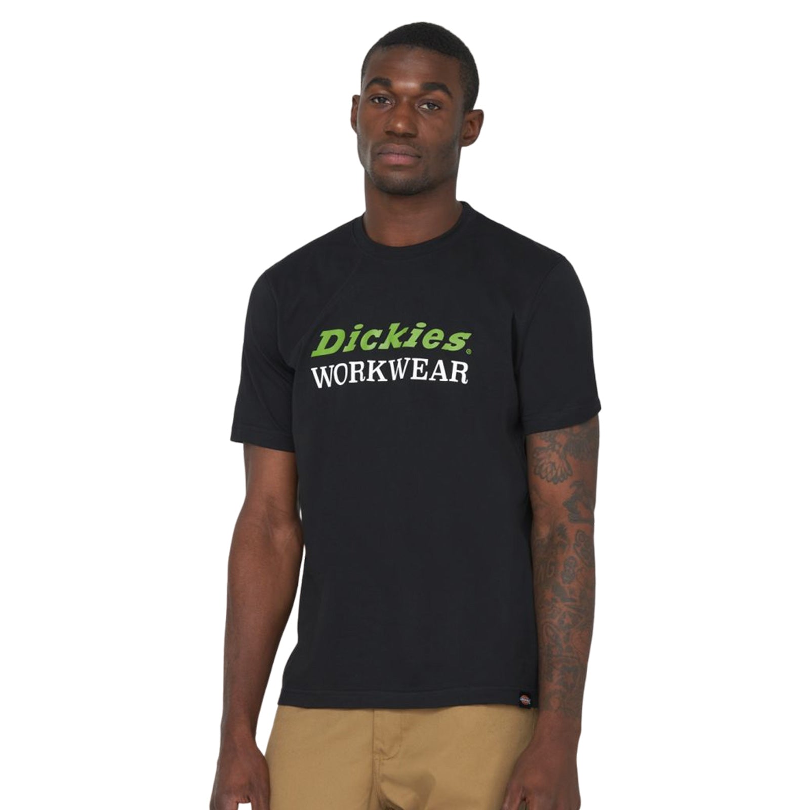 A man stands confidently wearing a black T-shirt with green and white text saying Dickies WORKWEAR in the foreground against a plain white background
