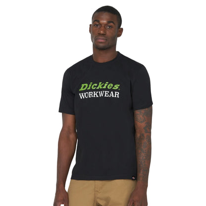 A man stands confidently wearing a black T-shirt with green and white text saying Dickies WORKWEAR in the foreground against a plain white background
