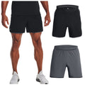 A person stands wearing black athletic shorts and white sneakers three pairs of shorts are displayed nearby in black and gray colors showcasing their design and style.
