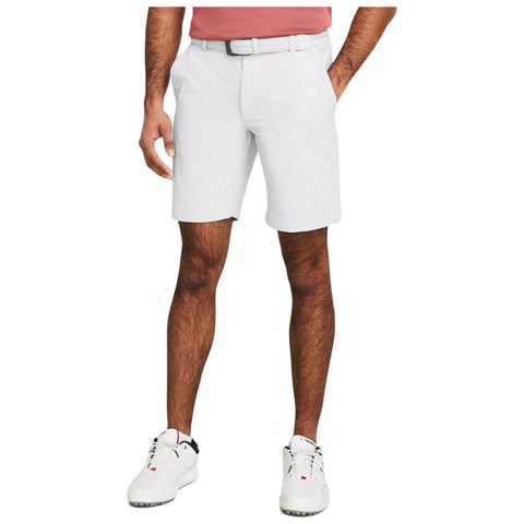 A pair of white shorts worn by a person standing with hands in pockets in a casual outdoor setting, complemented by a pink shirt and white athletic shoes.