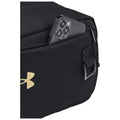 A black bag contains a smartphone partially placed in its zippered pocket displaying the brand logo nearby showcasing a practical storage solution for personal items in an everyday setting