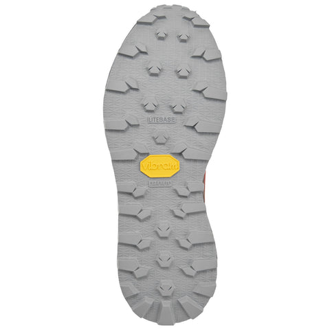 A gray shoe sole features a rugged tread design with various shapes and patterns providing traction significant for outdoor activities and sporting contexts with a yellow vibram logo prominently displayed.