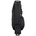 A black golf travel bag stands upright with telescopic handles extended providing a means to roll it. The bag is designed for transportation of golf clubs and equipment.