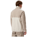 A person is wearing a light-colored fleece jacket with a high collar and a two-tone design. They are standing with their back facing the viewer against a plain background.