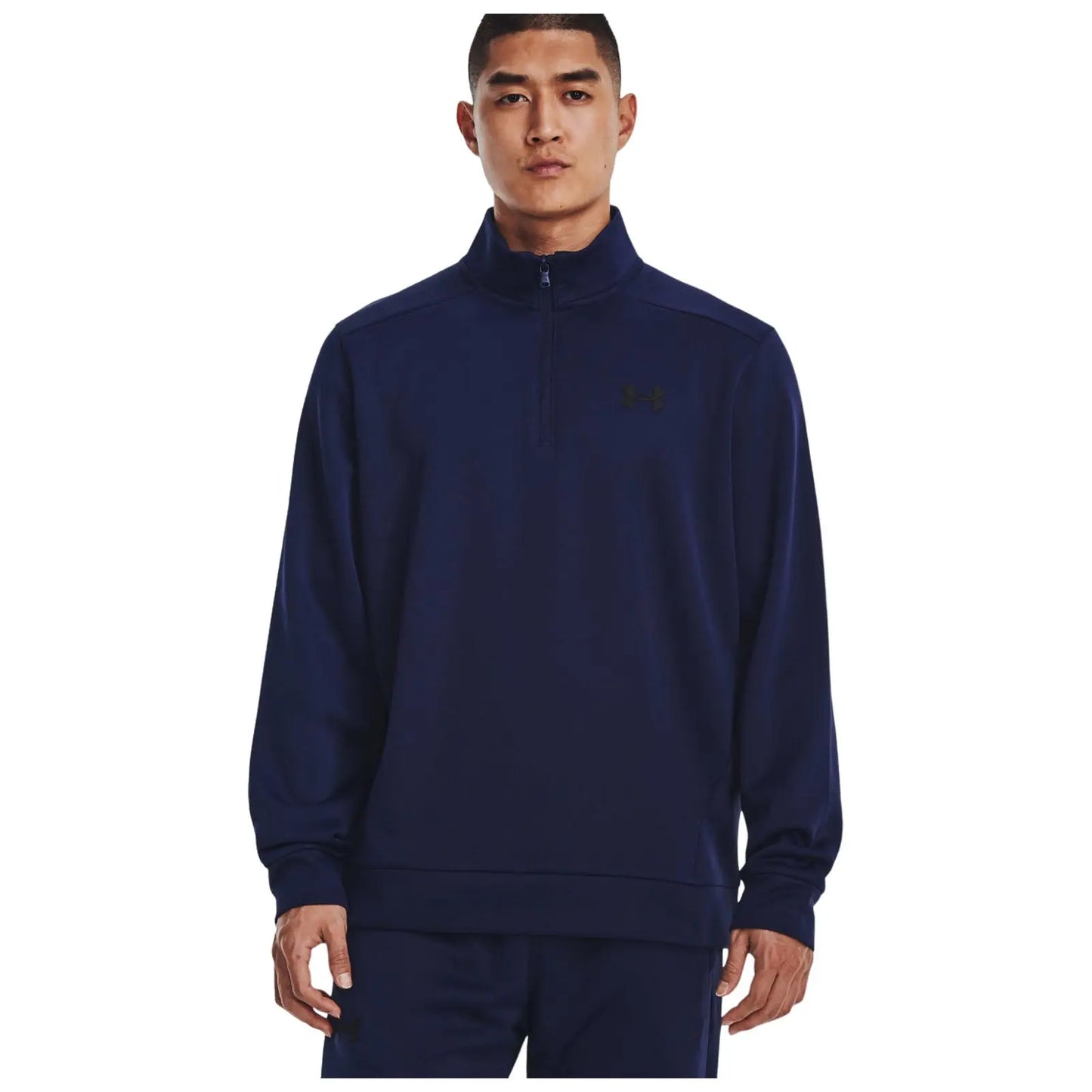 A man wearing a navy blue zip-up sweatshirt stands facing the camera with a neutral expression his hands at his sides showcasing a casual athletic style amidst a plain white background