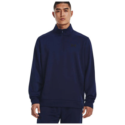 A man wearing a navy blue zip-up sweatshirt stands facing the camera with a neutral expression his hands at his sides showcasing a casual athletic style amidst a plain white background