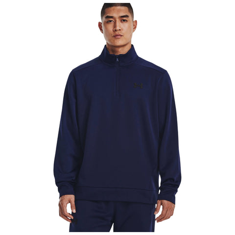 A man wearing a navy blue zip-up sweatshirt stands facing the camera with a neutral expression his hands at his sides showcasing a casual athletic style amidst a plain white background