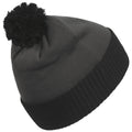 A knitted beanie with a black pom-pom sits upright displaying a folded ribbed band at the bottom and a smooth top in a dark gray color