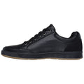 A black sneaker is positioned sideways with a smooth leather exterior and six eyelets for laces the rubber sole has a textured grip surface suitable for casual wear or activities