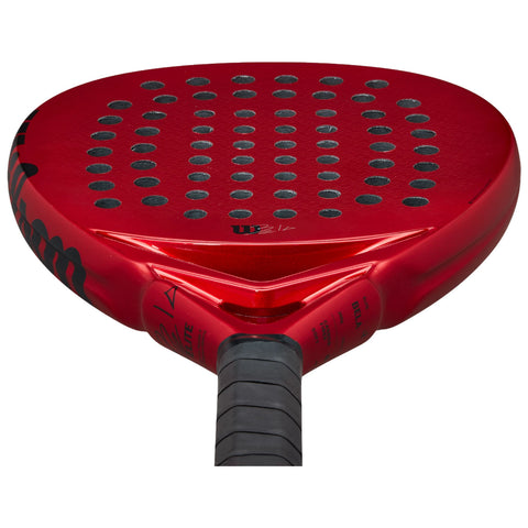 A red paddle racket features a rounded surface with numerous black holes for grip and ball control it has a tapered handle for easier handling in a sports context
