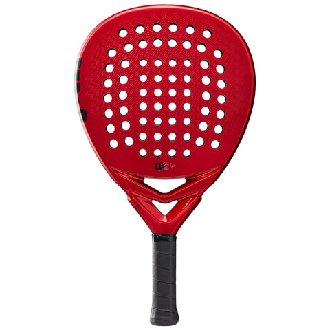 A red paddle with a perforated surface and a textured grip is positioned upright showcasing its frame and striking color for use in racket sports.