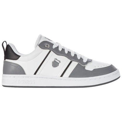 A gray and white sneaker is positioned on a flat surface with a sleek design featuring a logo on the side and laces threaded through eyelets creating a casual sports aesthetic.