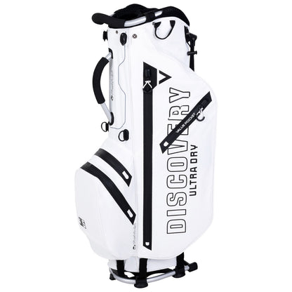 A white golf bag stands upright featuring multiple zippered pockets and a prominent logo. It is designed for carrying golf clubs and accessories, suitable for use on a golf course.