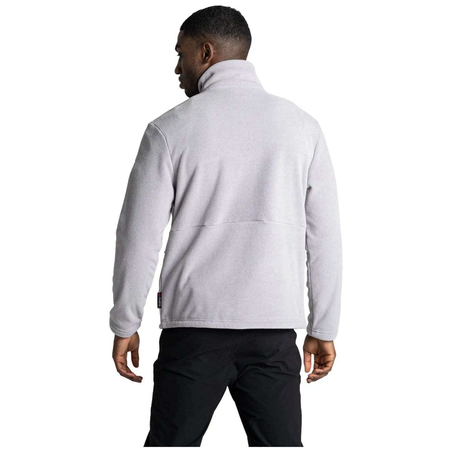 A person is wearing a light gray fleece jacket with a high collar while facing slightly away from the viewer in a neutral background setting.