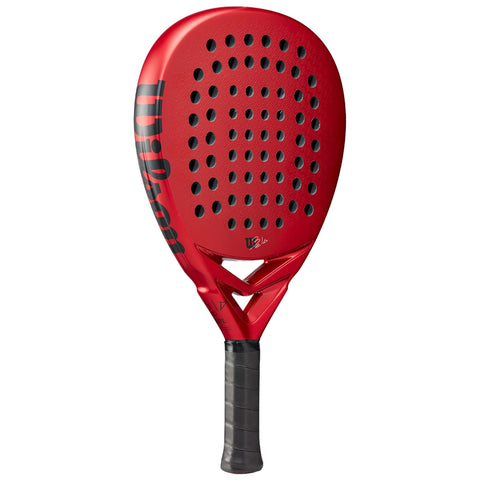A red paddle racquet with a perforated surface is positioned upright against a neutral background showcasing its sleek, aerodynamic design and textured grip for enhanced handling during gameplay.