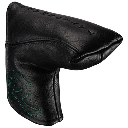 A black leather golf headcover with a pointed shape is designed to protect a golf club head while resting against a neutral background displaying a stitched logo in green.