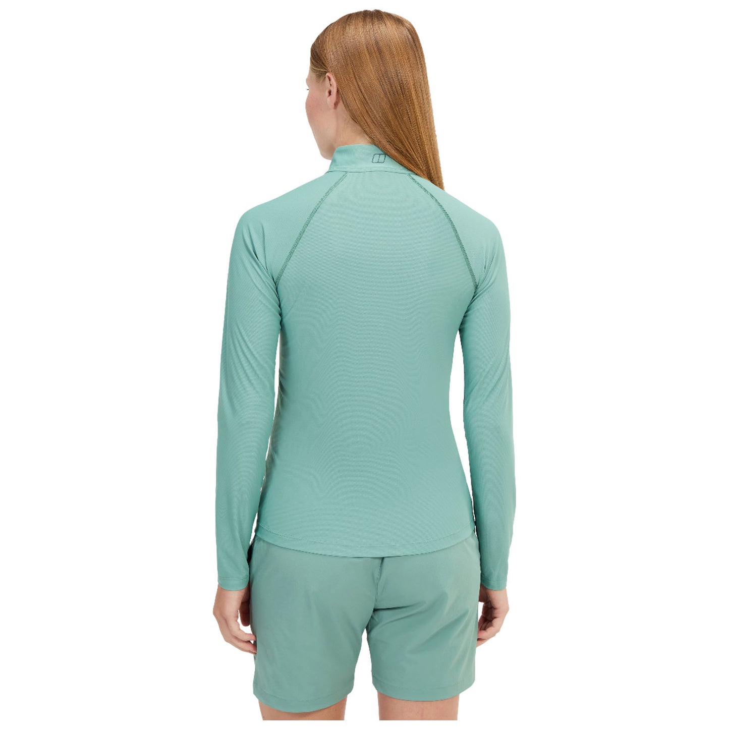 A blue long-sleeved athletic shirt is displayed on a model who poses with a slight head turn. The background is plain, focusing attention on the shirt design and fit.