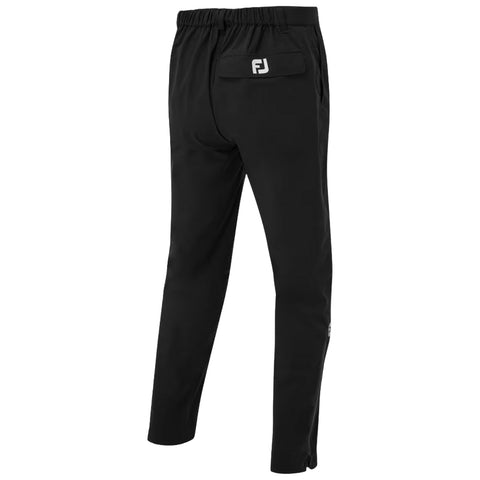 A pair of dark navy golf pants stands upright showcasing a sleek design with a button front and a small logo on the left leg ideal for outdoor sporting activities.