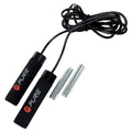 A jump rope with black foam handles lies coiled alongside two metallic weights on a plain background. The rope is designed for fitness activities.