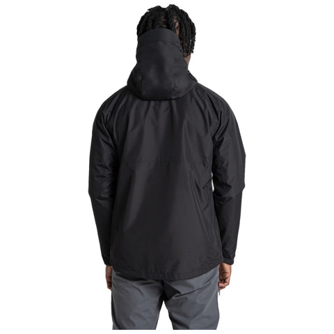 A person is standing wearing a black jacket with a hood and gray pants showing the back view with the focus on the jacket in an undefined, clean background.