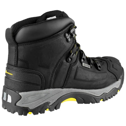 A black hiking boot features a rugged design with yellow accents and metal eyelets for laces positioned on a gray sole, designed for durability in outdoor settings.