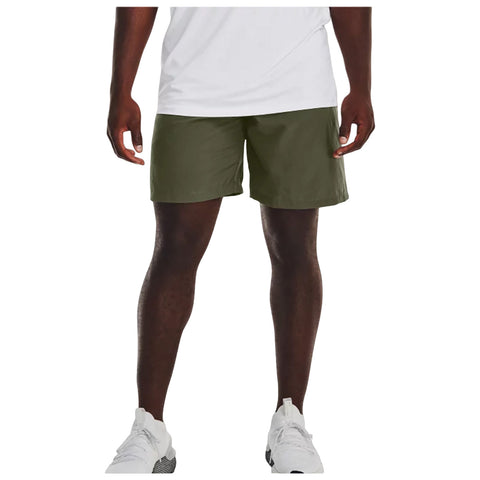 A person stands wearing green shorts and white athletic shoes with a partially visible white shirt the setting is casual likely outdoors or in a gym environment