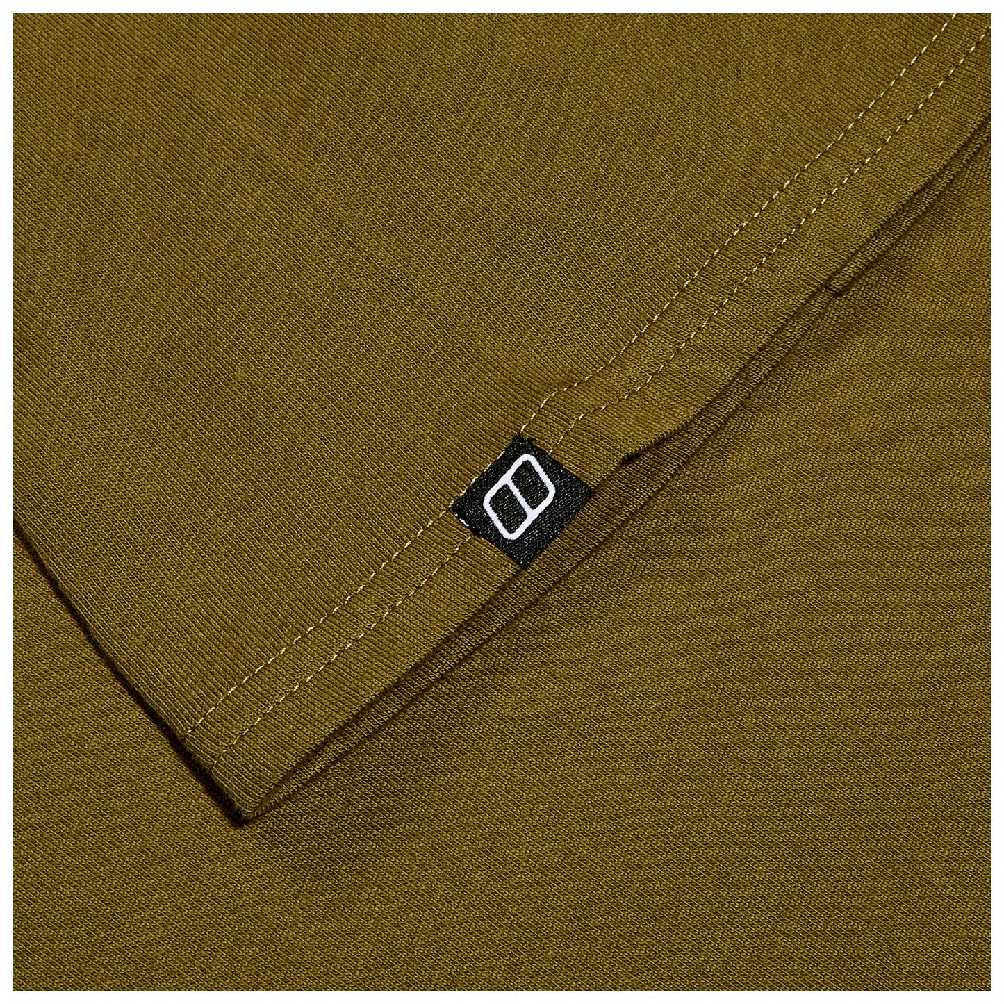 A folded piece of olive green fabric shows a black label with a white logo in the corner while the surrounding texture is smooth and consistent throughout.