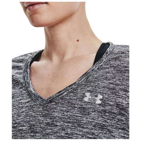 A close-up view of a person’s neckline wearing a grayish-black athletic shirt featuring a v-neck design with a visible logo on the fabric and a black inner layer underneath.