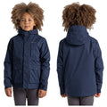 A child with curly hair is wearing a dark blue jacket with a hood and two front pockets while standing upright against a plain white background.