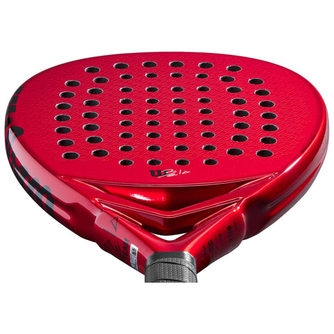 A red paddle racket with a perforated surface rests in a horizontal position showcasing its sleek design and grip area ideal for racket sports.