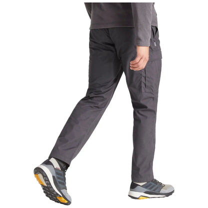 A person walks while wearing gray cargo pants and hiking shoes. The setting is neutral with a focus on the individual's clothing and footwear.