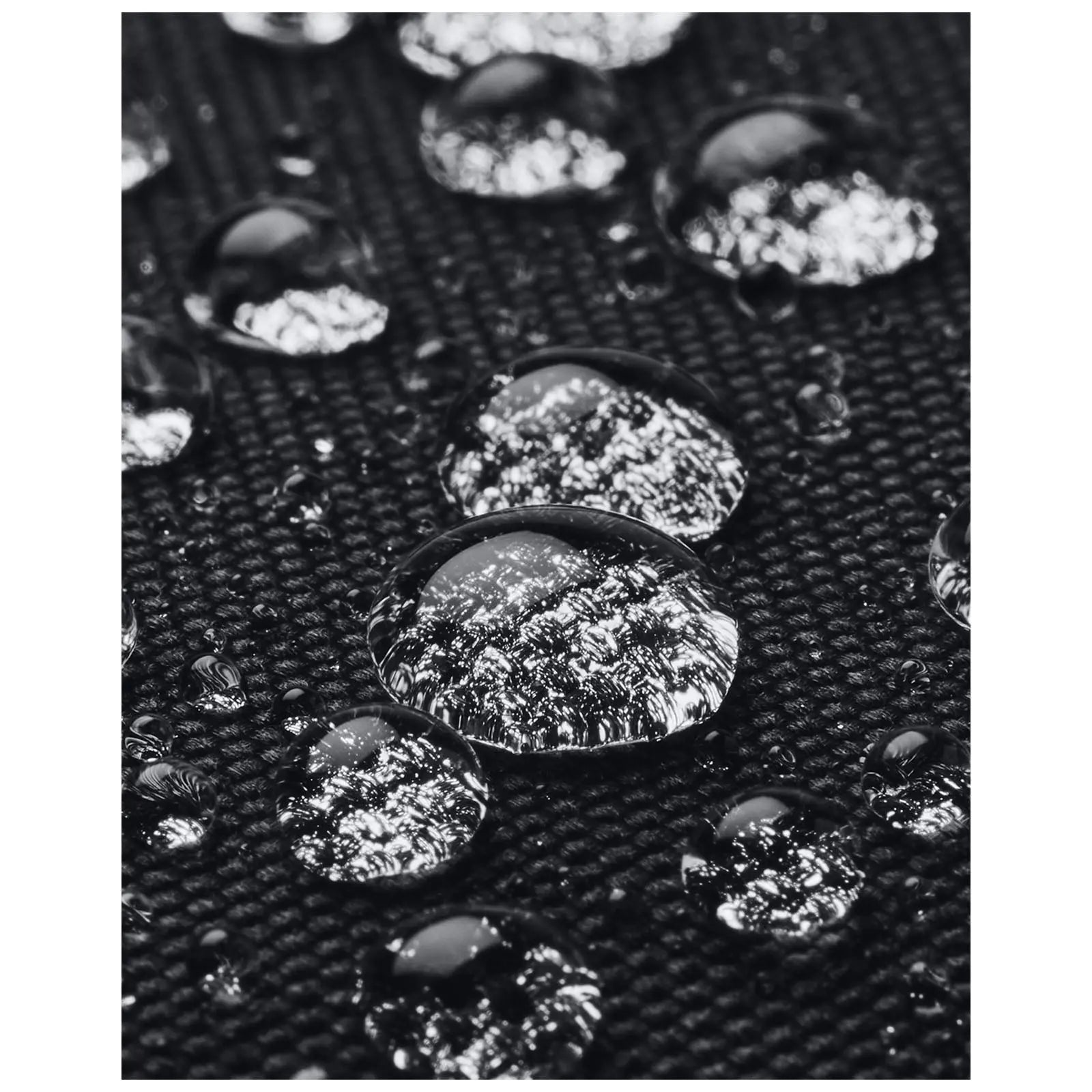 Water droplets rest on a textured black surface reflecting light while appearing clear and glossy in a close-up view showcasing the contrast between the droplets and the background.