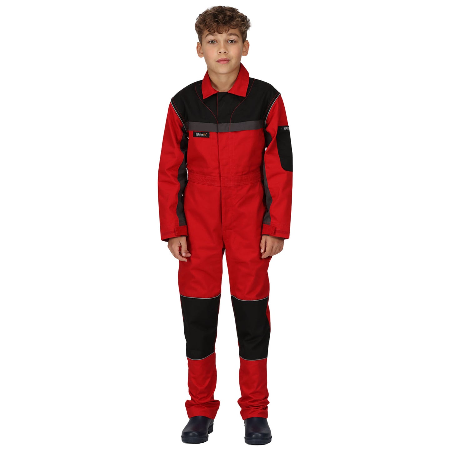 A young person is standing still wearing a bright red and black jumpsuit with long sleeves and legs paired with black shoes in a plain white background.