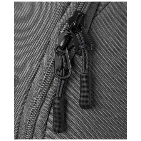 A gray backpack is shown with a close-up of its zippers closed with black pulls that have textured grips set against a fabric surface with a subtle weave pattern.