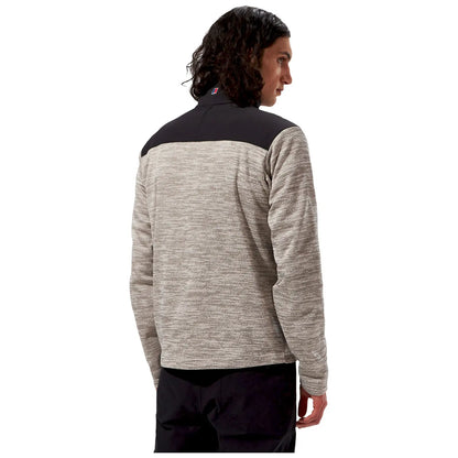 A man with curly hair is wearing a gray and black long-sleeve shirt while facing away from the viewer in a plain white background