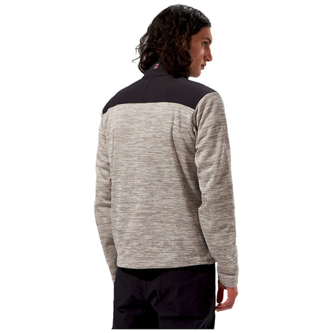 A man with curly hair is wearing a gray and black long-sleeve shirt while facing away from the viewer in a plain white background