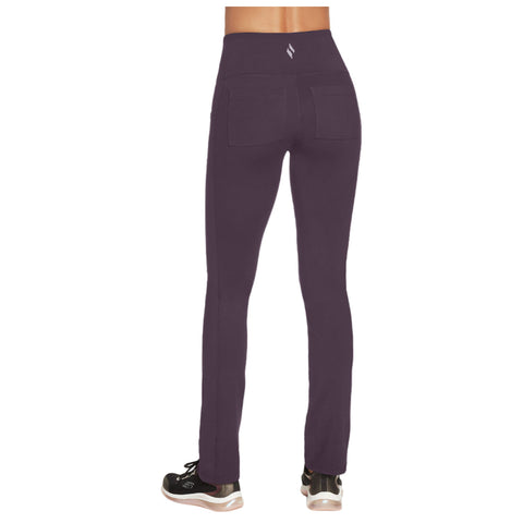 A person is wearing dark purple leggings with a high waist and pockets while standing. The setting is likely casual or athletic, paired with black sneakers.