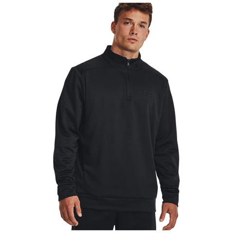 A young man stands wearing a black, long-sleeved pullover with a quarter zip and a logo on the chest showcasing a casual sporty style against a plain white background.