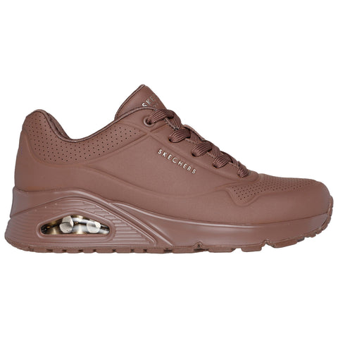 A brown athletic sneaker featuring a smooth upper surface and visible air cushioning in the sole is displayed on a white background showcasing its design and brand logo.